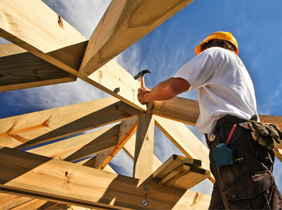 Carpenter hammering a nail into the frame of a custom built house