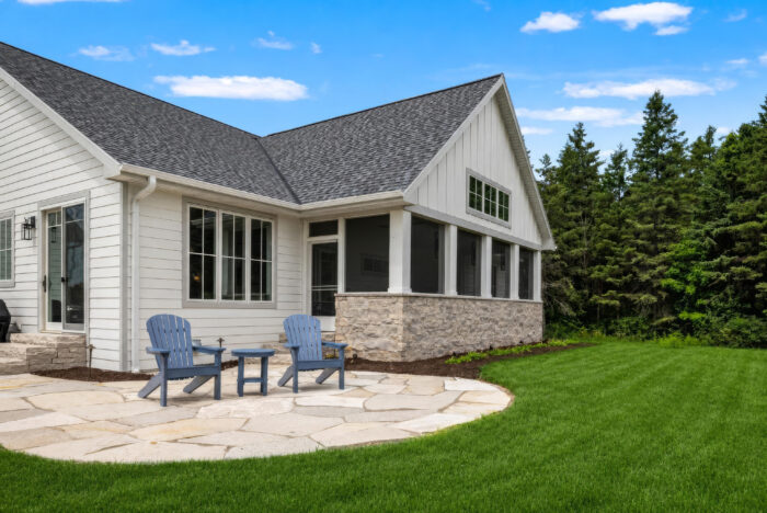 Van's Lumber custom built homes in Northeast Wisconsin rear exterior of custom built home with stone patio and sunroom