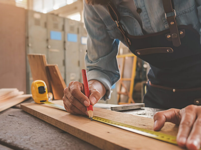 Close up of a carpenter measuring and marking a wood beam in a custom built home