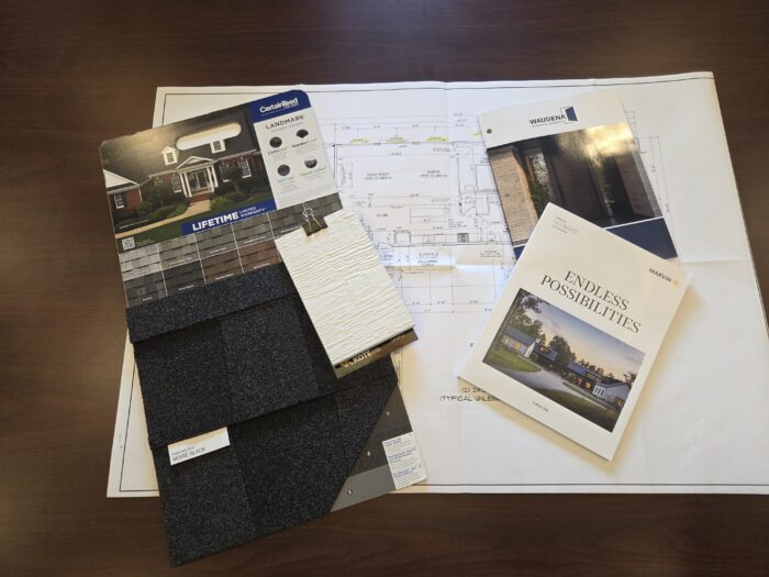 Image of a floor plan with option for shingles, flooring, and other items fanned out on top