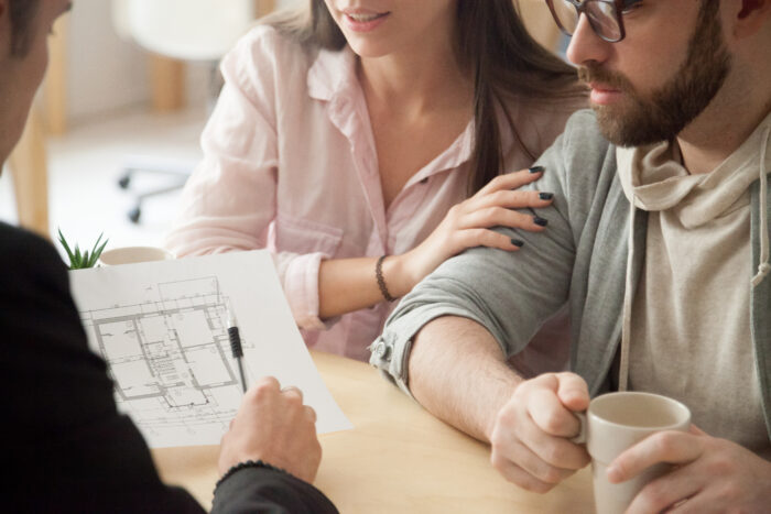 Couple meeting to learn about designing a custom built home looking at a floorplan with consultant